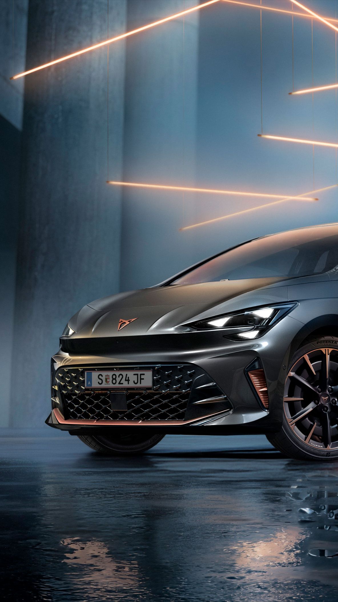 Ein grauer CUPRA Born steht in einer modernen, dunklen Umgebung mit vertikalen Säulen und leuchtenden LED-Streifen. Der Boden ist glänzend und reflektiert das Fahrzeug sowie die Beleuchtung. Das Auto wirkt kraftvoll und elegant.