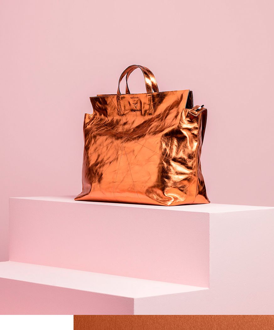 Auf dem Bild ist eine Tasche in Kupfer-Metallic auf blassrosa Hintergrund