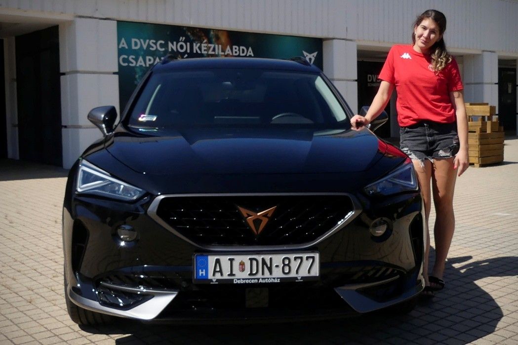 cupra modell mellett egy piros felsős fiatal lány áll