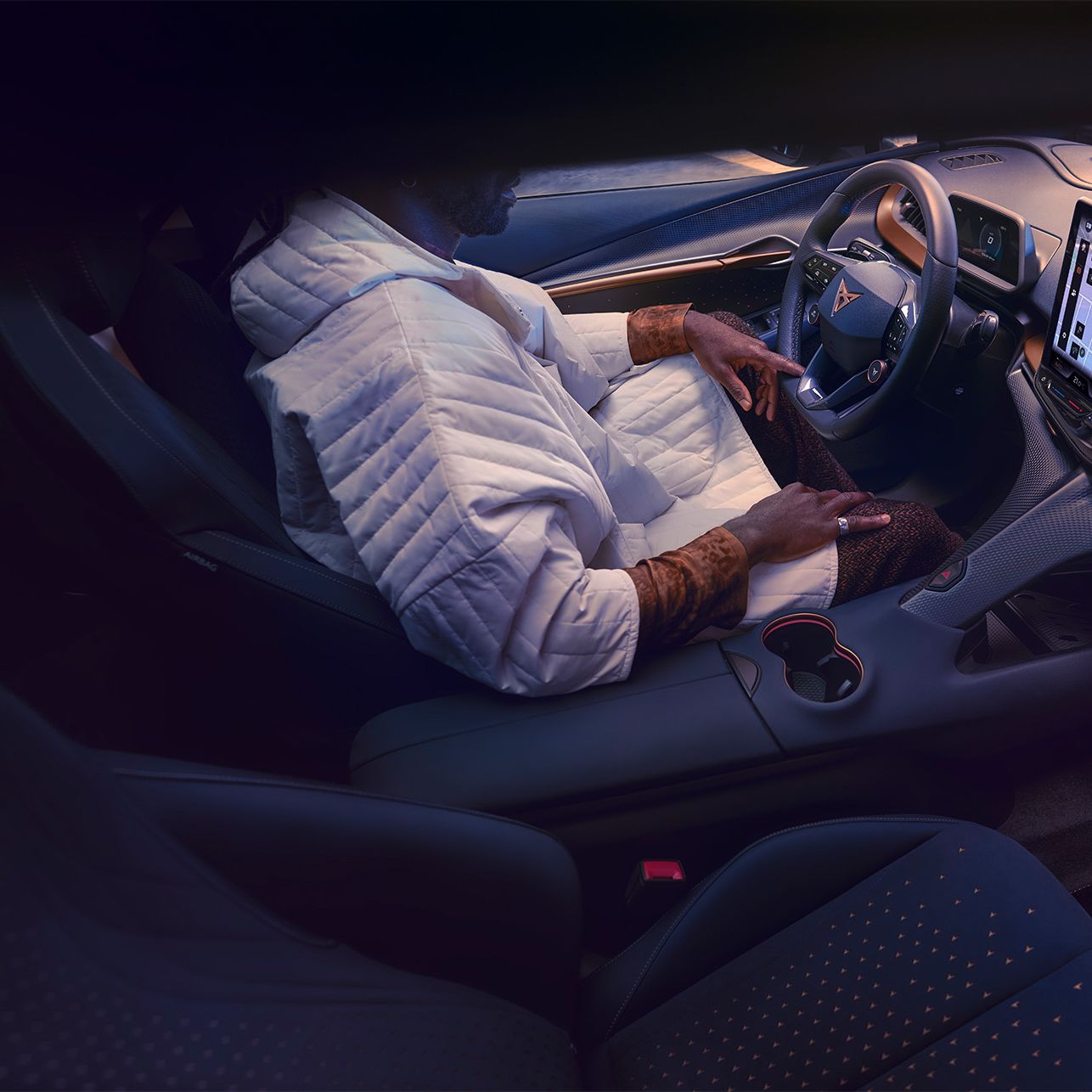 CUPRA Tavascan vezetőülésénél ül egy férfi