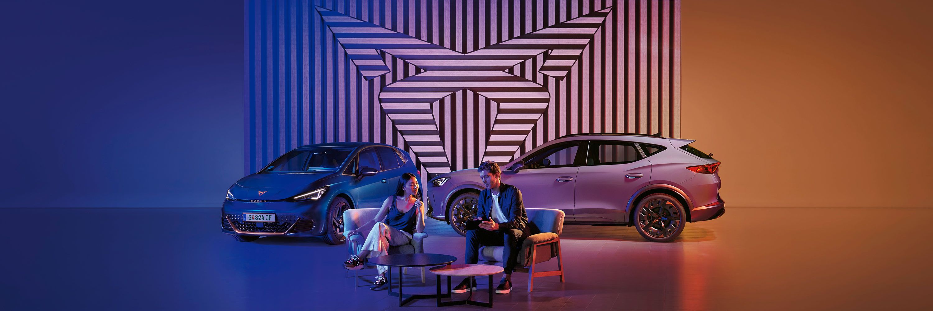 Zwei CUPRA Modelle-ein Mann und eine Frau sitzen davor