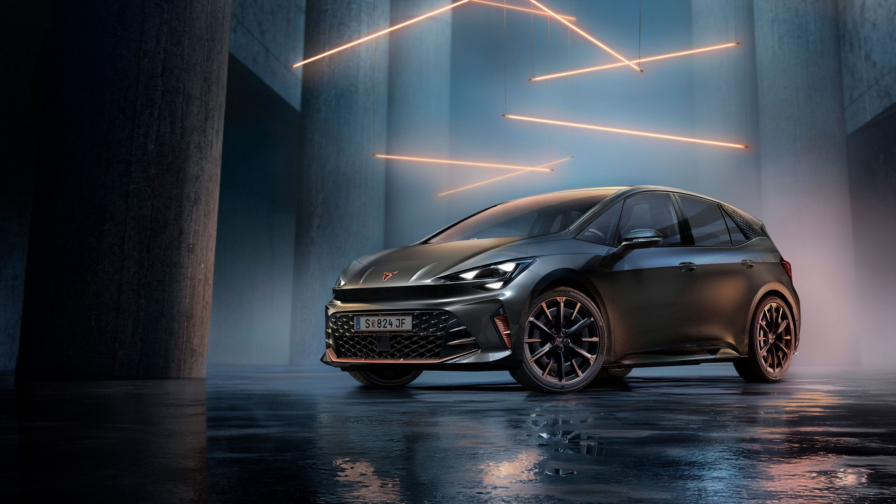 Ein grauer CUPRA Born steht in einer modernen, dunklen Umgebung mit vertikalen Säulen und leuchtenden LED-Streifen. Der Boden ist glänzend und reflektiert das Fahrzeug sowie die Beleuchtung. Das Auto wirkt kraftvoll und elegant.