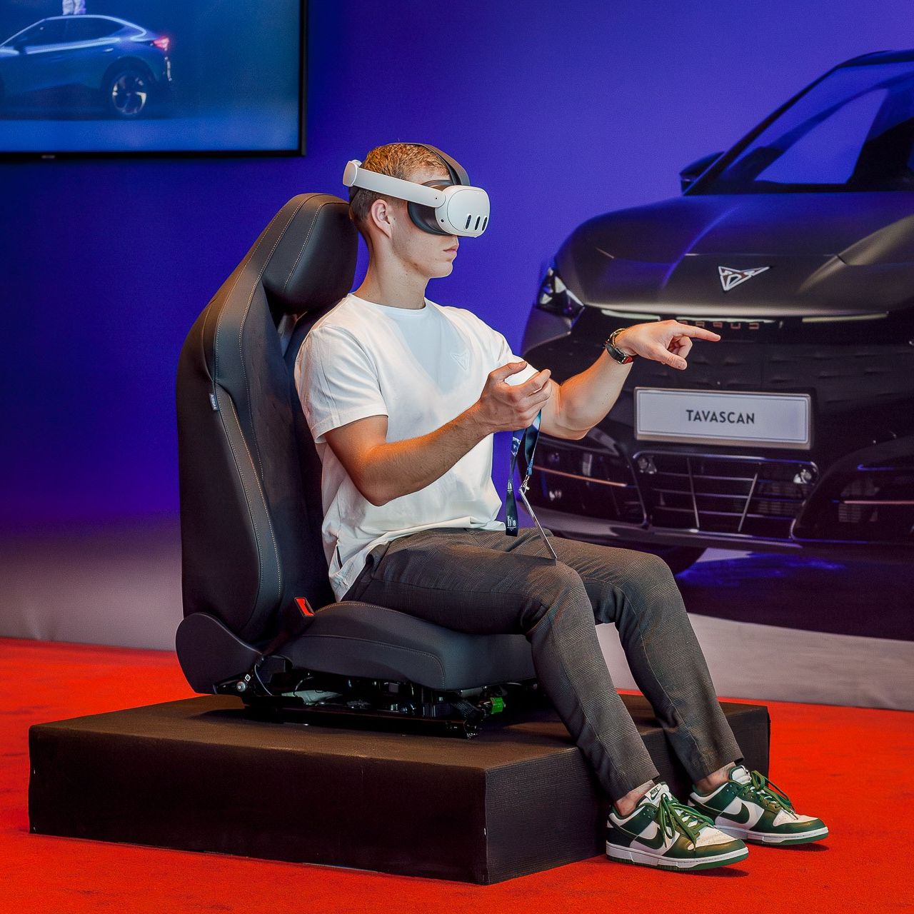 Egy férfi VR szemüvegben ül, mögötte egy CUPRA Tavascan