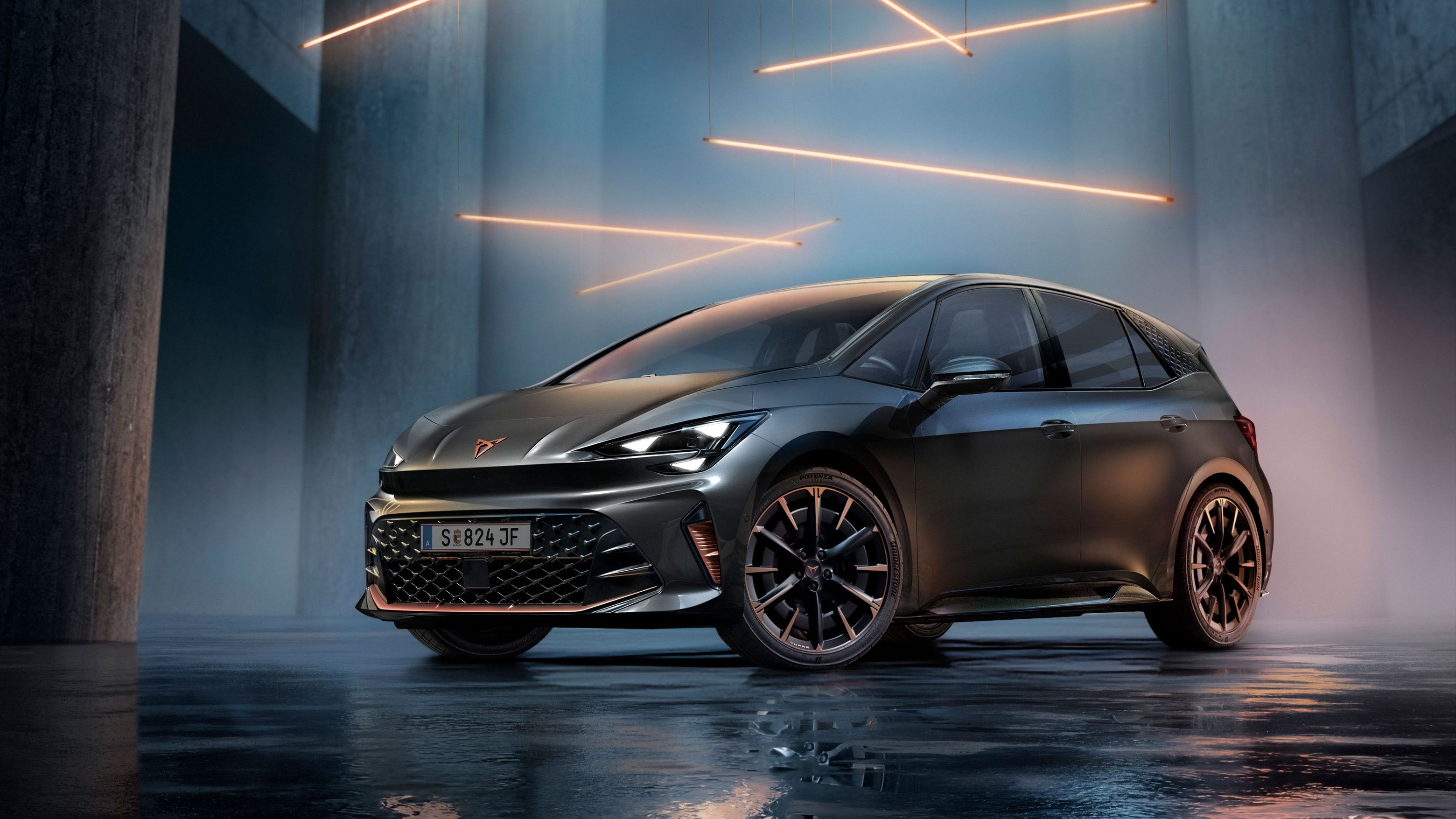 Ein grauer CUPRA Born steht in einer modernen, dunklen Umgebung mit vertikalen Säulen und leuchtenden LED-Streifen. Der Boden ist glänzend und reflektiert das Fahrzeug sowie die Beleuchtung. Das Auto wirkt kraftvoll und elegant.