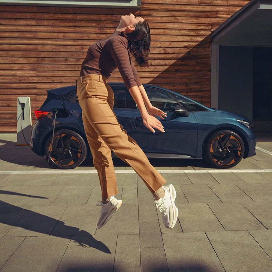 CUPRA Born mellett egy nő az ég felé néz